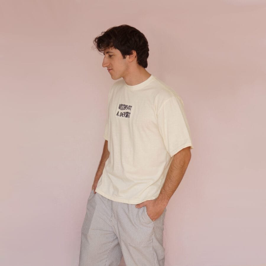Male model facing forward in a cream-colored oversized T-shirt with front text.
