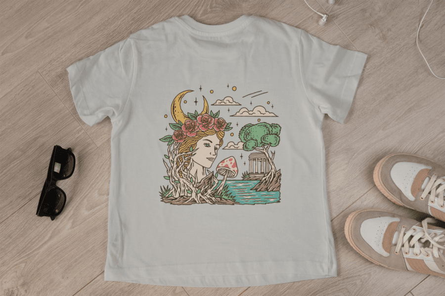 Top-down view of a white T-shirt featuring a Greek-inspired Gaia design with a woman’s face, moon, flowers, and temple details.